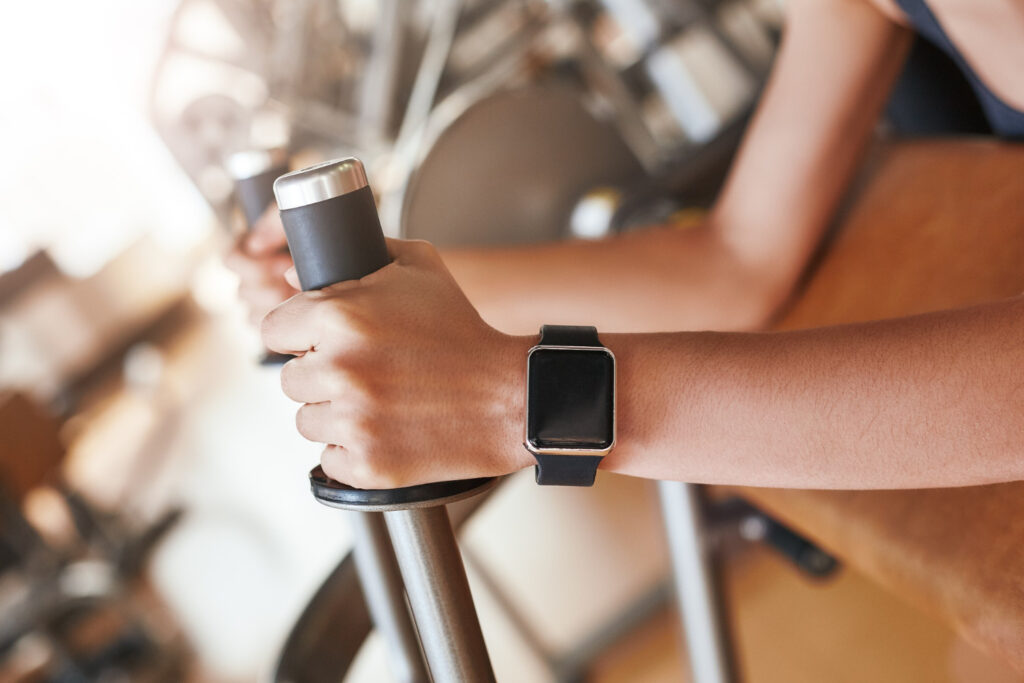 Vue de près d'un bras portant une montre connectée, tenant la poignée d'un appareil de fitness.