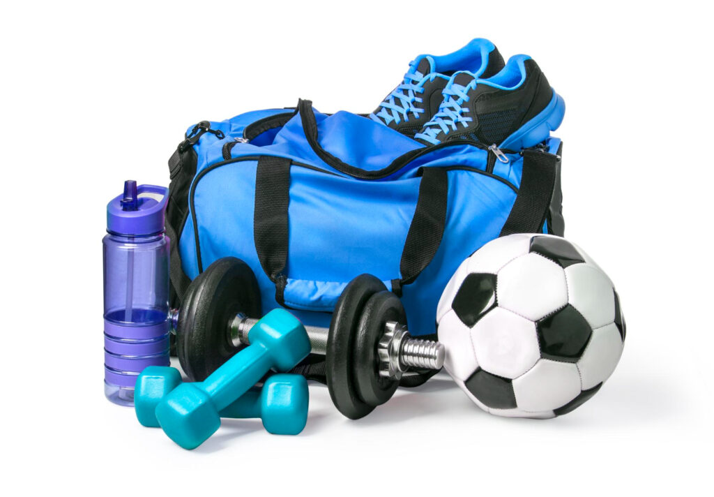 Un sac de sport bleu et noir avec divers accessoires et matériels: un ballon de foot, des haltères, des baskets et une gourde violet.